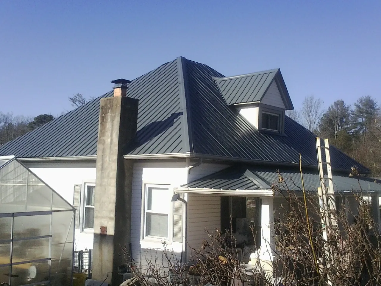 Dark blue standing seam metal roof on a white farmhouse with dormer — Slate & Tile Roof Repair by Roofing Brothers in Holland Patent