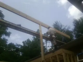 Carpenter setting a ridge beam over a new addition frame — Ice Dam Removal by Roofing Brothers in Holland Patent