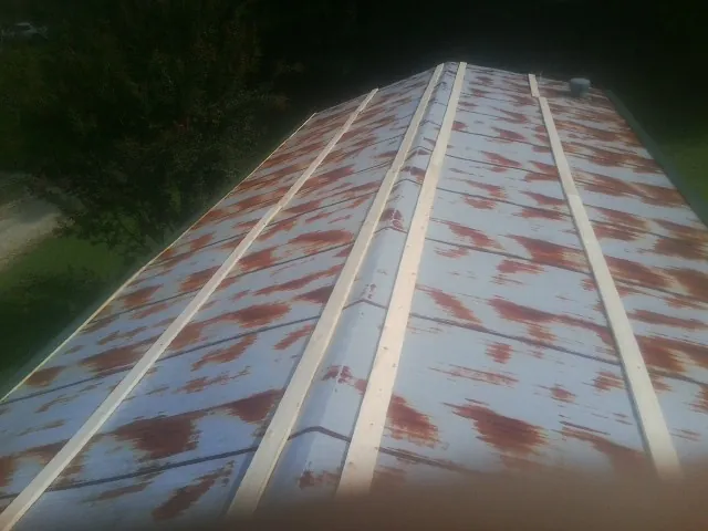 Rusted metal roof panels with new wood purlins before replacement — Storm Damage Roof Repair in Holland Patent by Roofing Brothers
