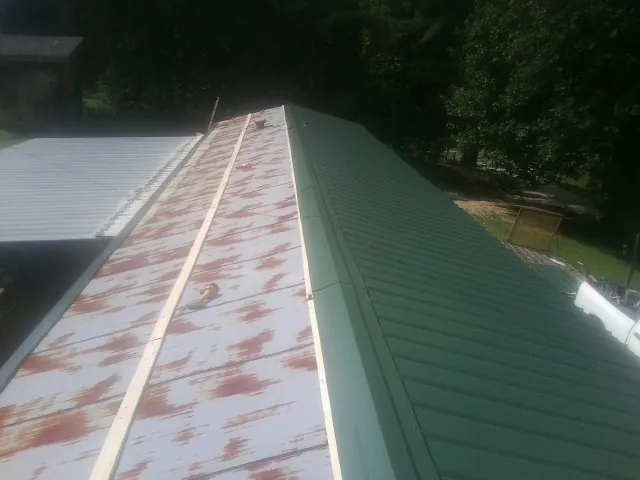 Old rusted panels beside newly installed green metal roofing — Wind Damage Roof Repair by Roofing Brothers in Holland Patent