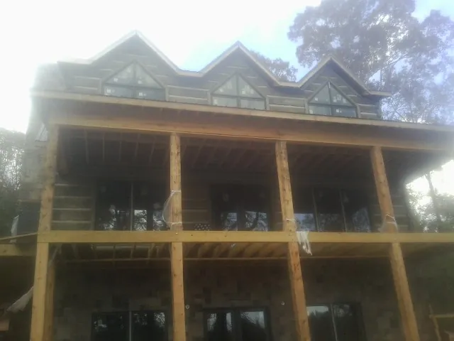 Dormers and porch framing on a large log home under construction — Roof Coating work by our crew in Holland Patent