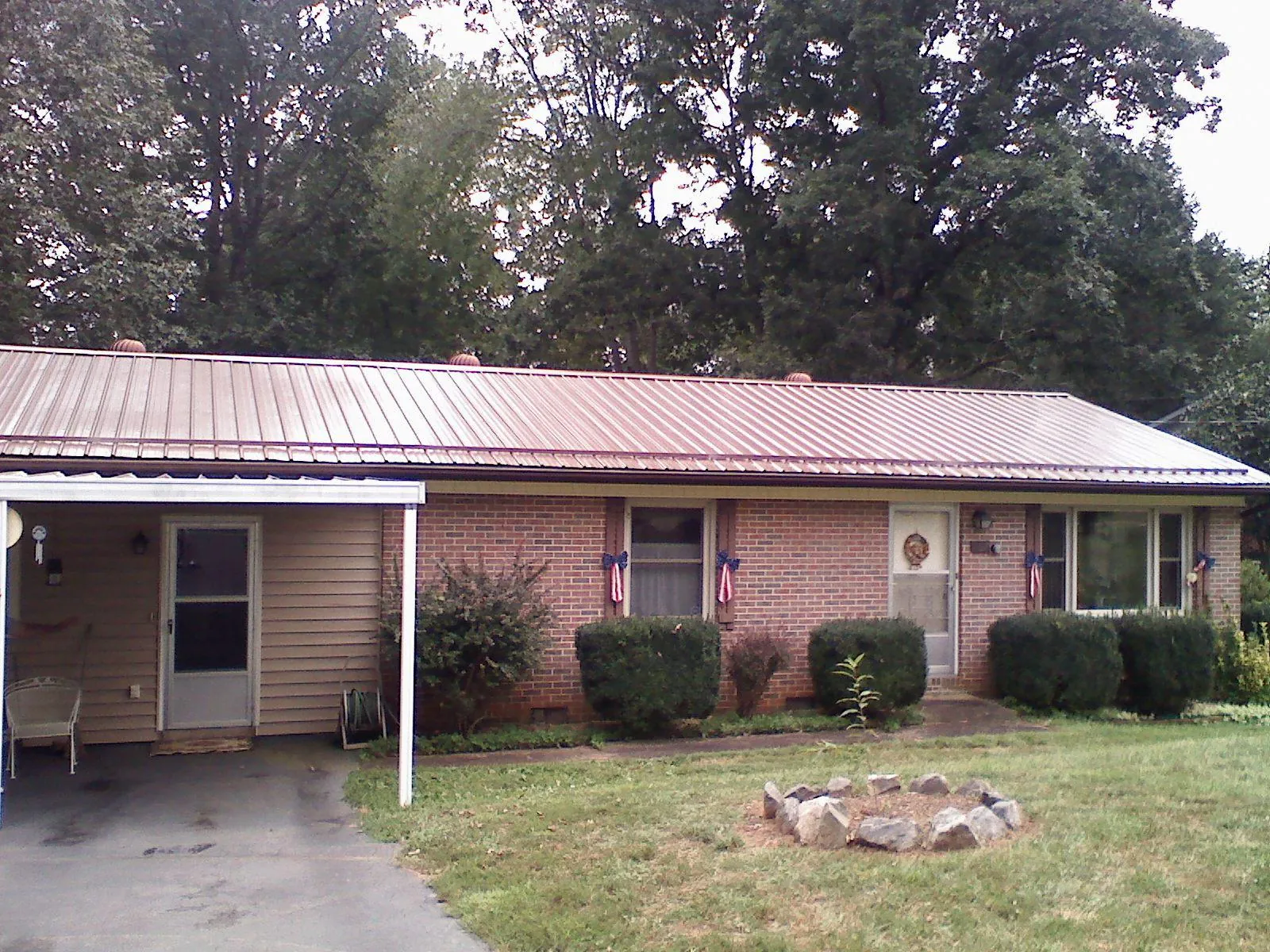 Bronze metal roof and carport on a brick ranch home — Roof Repair work by our crew in Holland Patent