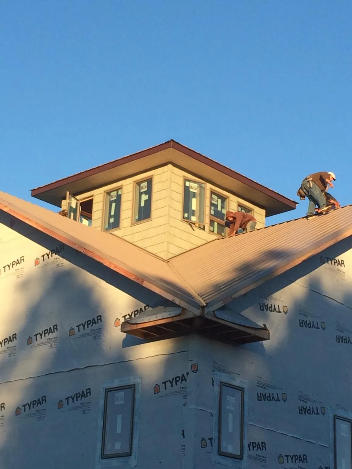 Roofers working around a rooftop cupola on a new metal roof at sunset — Roof Waterproofing in Holland Patent by Roofing Brothers